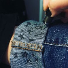 someone is cutting their jeans with a pair of scissors and some writing on the side