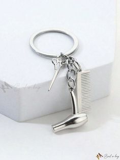 a close up of a keychain with a comb and scissors attached to it