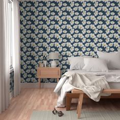 a bed sitting in a bedroom next to a wooden table and lamp on top of a hard wood floor