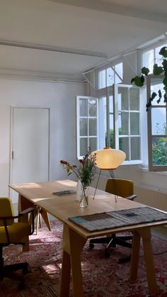 a room with several chairs and a table in front of a large window filled with plants