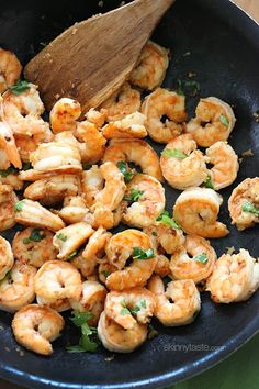 cooked shrimp in a skillet with a wooden spoon