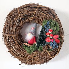 a wreath with gnomes, mushrooms and berries in the shape of a bird's nest