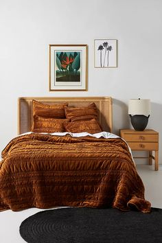 a bedroom with a bed, nightstands and pictures on the wall above it is shown