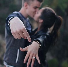 a young man and woman are kissing while pointing their fingers at each other's forehead