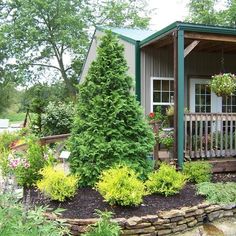 a small house with trees and flowers in the front yard