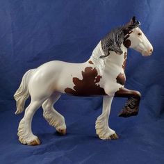 a white and brown horse figurine on a blue background with a black spot