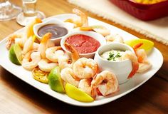 a white plate topped with shrimp and dipping sauces