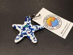 a blue and white star shaped keychain sitting on top of a black table