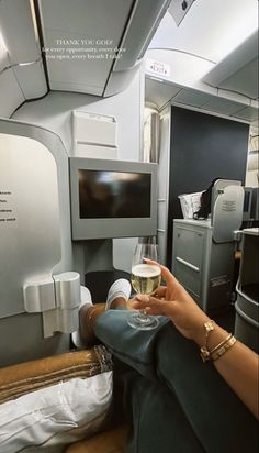 a woman holding a glass of wine on an airplane