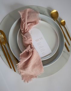 a white plate topped with a pink napkin and goldware next to a silver fork