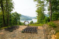 an outdoor ceremony set up with chairs and flowers in the foreground, overlooking a lake