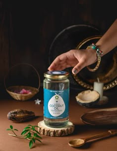 a hand reaching into a jar filled with coconut oil on top of a wooden table