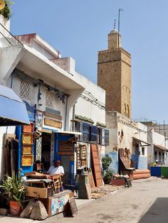 a man is sitting in front of his shop on the side of an alleyway