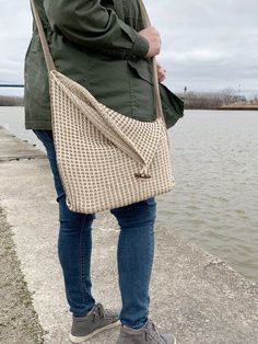 a woman is standing by the water with her purse