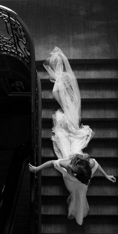 a woman in a white dress is walking down some stairs