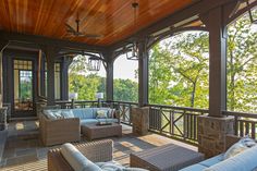 an outdoor covered porch with wicker furniture and wood ceilinging, overlooking the water