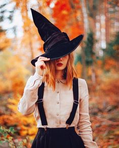 a woman wearing a witches hat in the woods