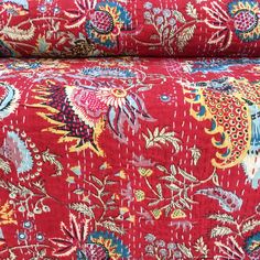 a red floral print fabric with many different colors and designs on the side, as well as