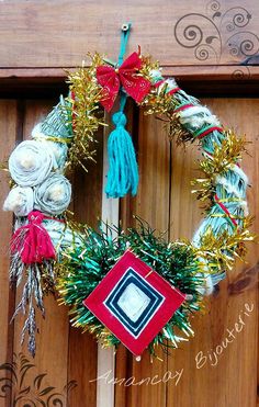 a christmas wreath hanging on a wooden door with ribbons and decorations around the wreath is an ornament