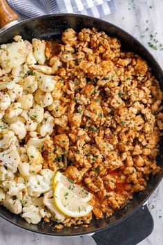 a pan filled with cauliflower and lemon wedges on top of a table