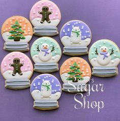 decorated sugar cookies with snowmen and christmas trees in glass domes on a purple background