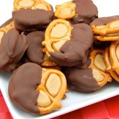 chocolate and peanut butter pretzels on a white platter with red table cloth