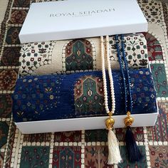 three necklaces with tassels are in a box on the carpeted floor