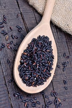 a wooden spoon filled with black seed on top of a table