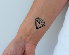 a small black diamond tattoo on the wrist