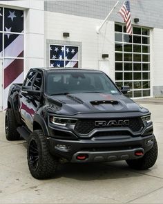 a black truck parked in front of a building with an american flag on it's side