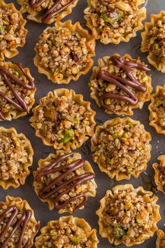 many small cupcakes with chocolate and nuts on top are lined up in rows