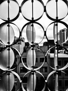 black and white photograph of circular windows with buildings in the background