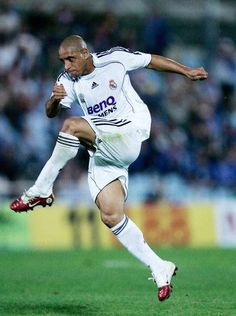 a man kicking a soccer ball on top of a field