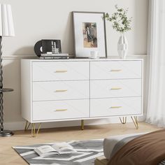 a white dresser sitting next to a bed in a bedroom