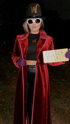 a woman in a red velvet coat and hat holding a sign that says golden ticket