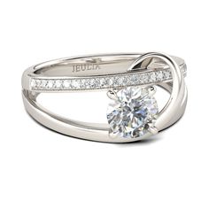 a white gold ring with diamonds on the band and a round cut diamond in the center