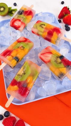 fruit pops are sitting on ice with strawberries, kiwis and blueberries