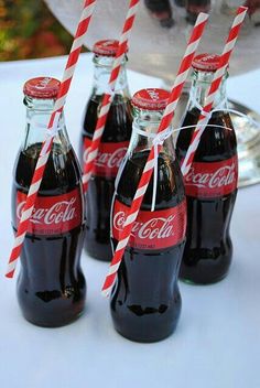 four coca - cola bottles with red and white striped straws in front of them