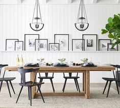 a dining room table with chairs and pictures on the wall above it, along with a potted plant