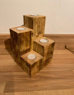 three wooden blocks with candles in them on a wood floor