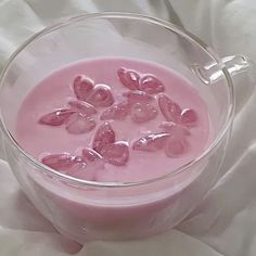 a glass bowl filled with pink liquid on top of a white cloth covered tablecloth