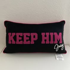 a black and pink pillow with the words keep him on it sitting on a white table