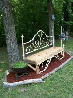 a wooden bench sitting next to a tree in the grass near a potted plant