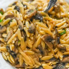 a plate full of pasta and mushrooms with a fork