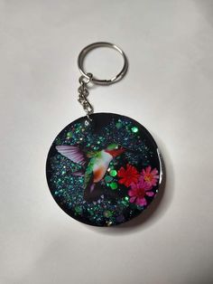 a keychain with a hummingbird and flowers on it's back side