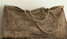 an old woven purse sitting on top of a wooden table next to a white wall