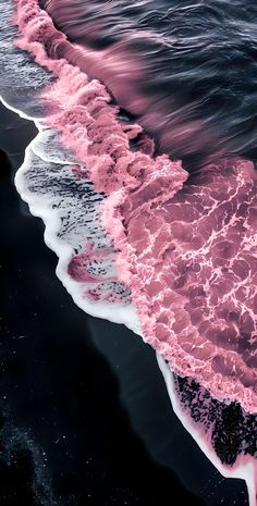 pink and black beach with waves coming in from the water