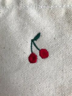 the embroidered cherries are red and green on white linen, which has been stitched together