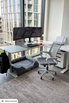 an office with a couch, computer desk and large window overlooking the cityscape