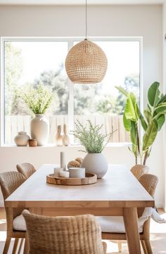 a dining room table and chairs with plants in vases